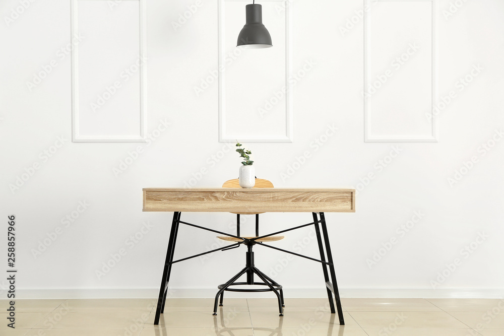 Wooden table near white wall in room Wooden table near white wall in room
