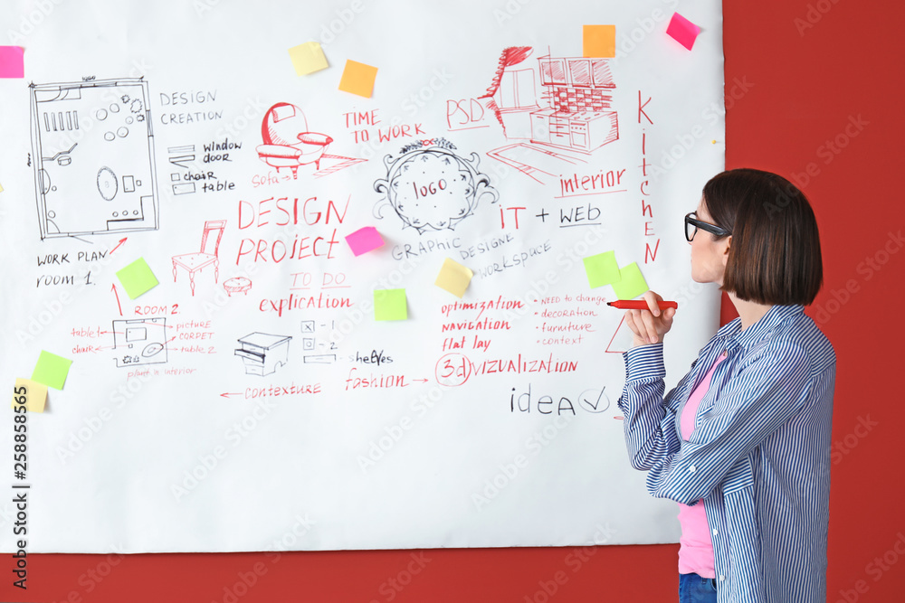 Fototapeta premium Female designer near big paper sheet with project plan in office