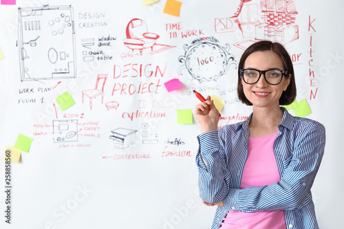 Female designer near big paper sheet with project plan in office