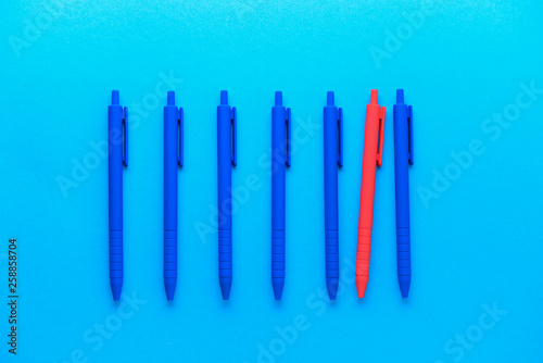 Red pen among blue ones on color background. Concept of uniqueness