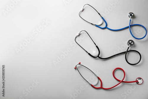 Medical stethoscopes on color background
