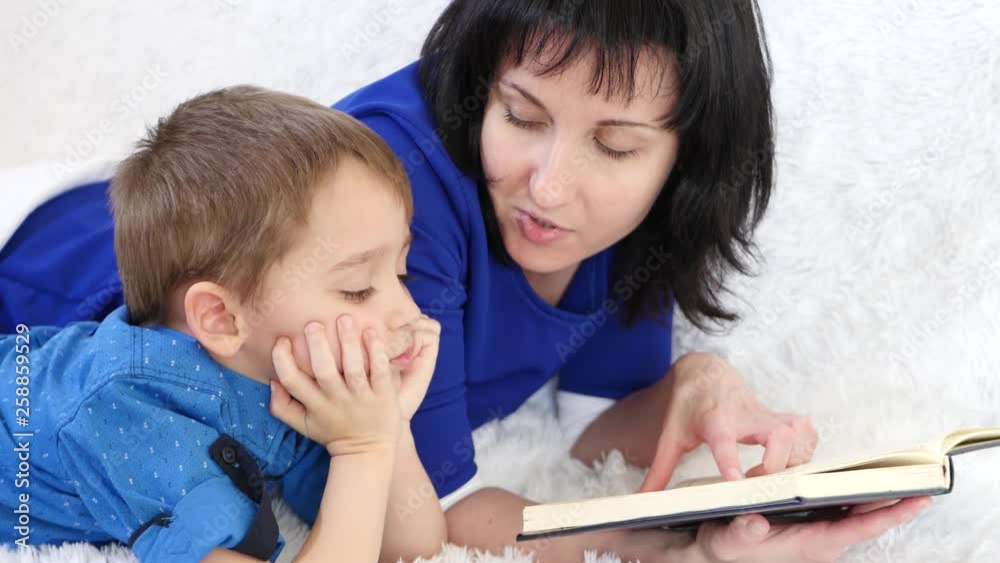 Mother reading a book to her little sons in the nursery. Happy family, lifestyle, parenting and education of children. Mother reading a book to her little sons in the nursery. Happy family, lifestyle, parenting and education of children.