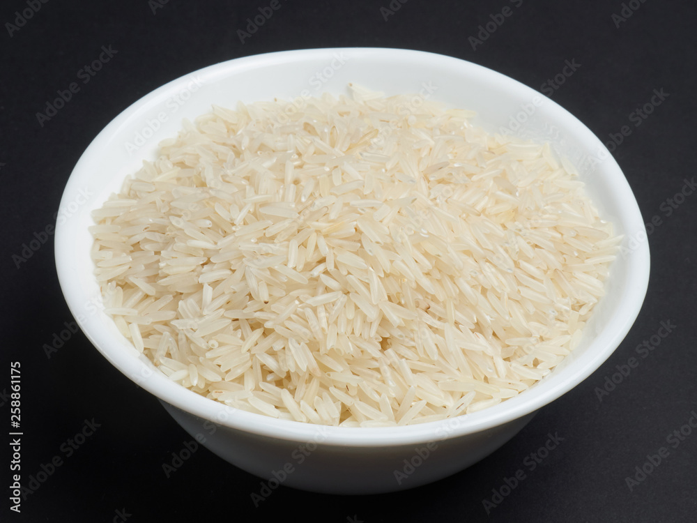 White basmati rice in a white bowl on a black background White basmati rice in a white bowl on a black background