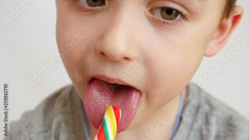 The child puts bright candy in his mouth and eats it. Close-up.