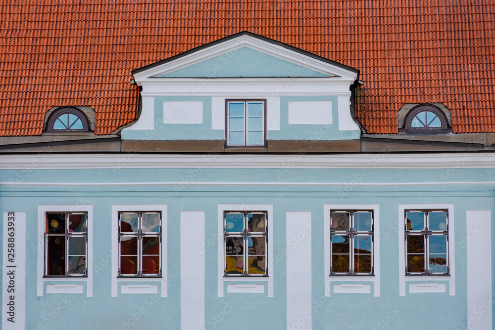 Obraz premium Facade of blue building with windows and red tile roof