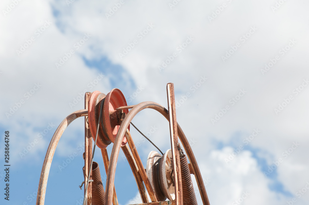 Mine shaft pulley from a low angle with sky and clouds behind