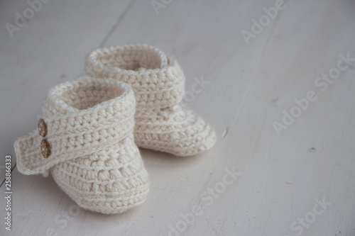 Newborn baby booties, beige, cozy and nice. Child clothe and boots - knitted and sweet. Text space, copy past and place for your design