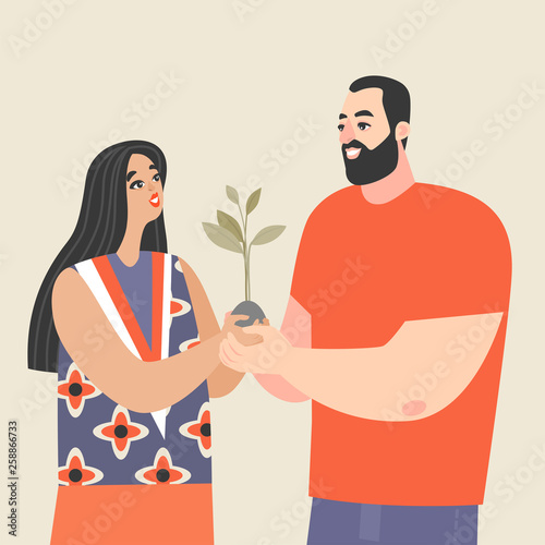 Young couple holding a sapling and smiling. Conceptual image of love and development of relationships