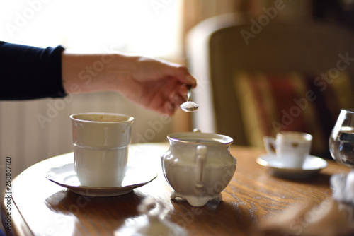 Hand adding sugar to coffee in cafe