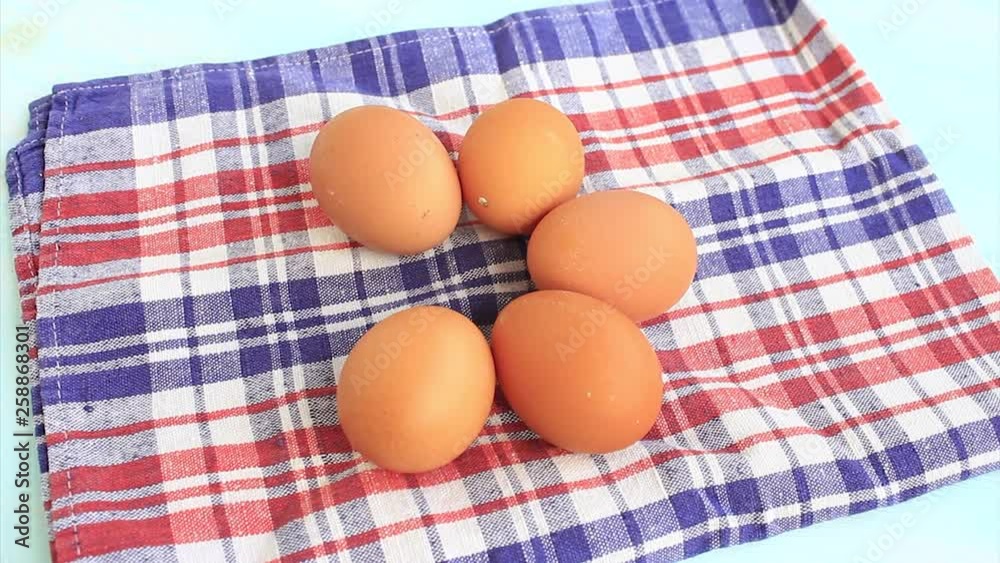 A hand is putting a fresh, raw organic egg on a napkin. A hand is putting a fresh, raw organic egg on a napkin.