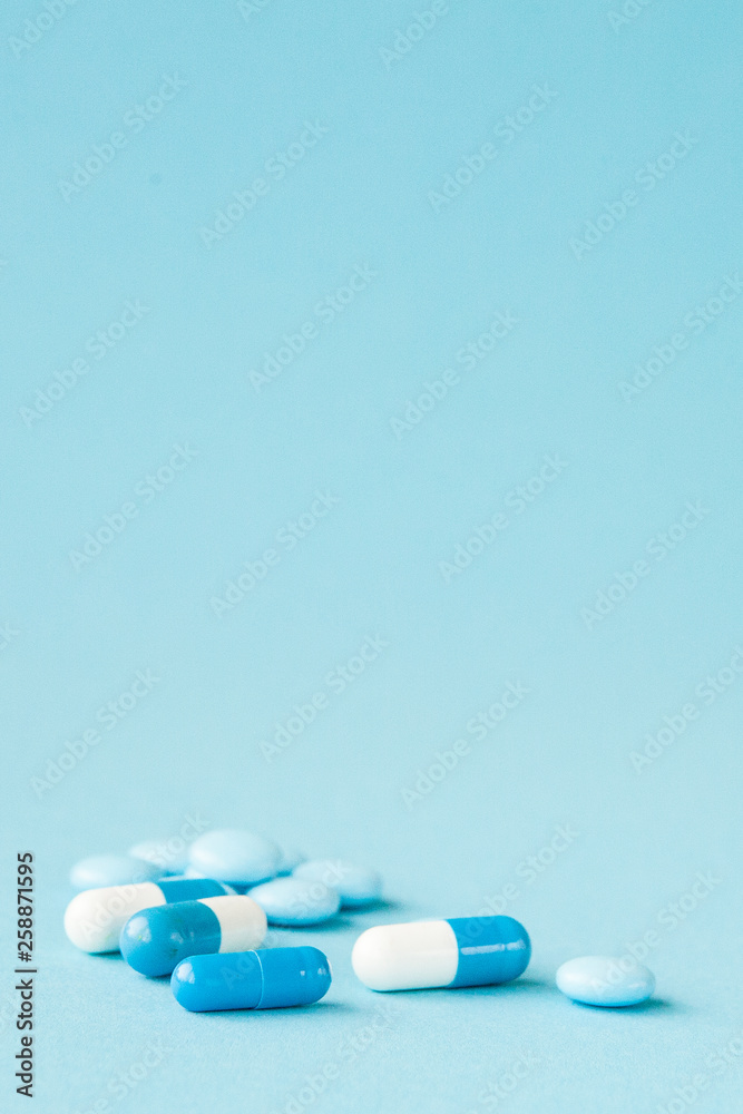 Blue pills and capsules on blue background with copy space