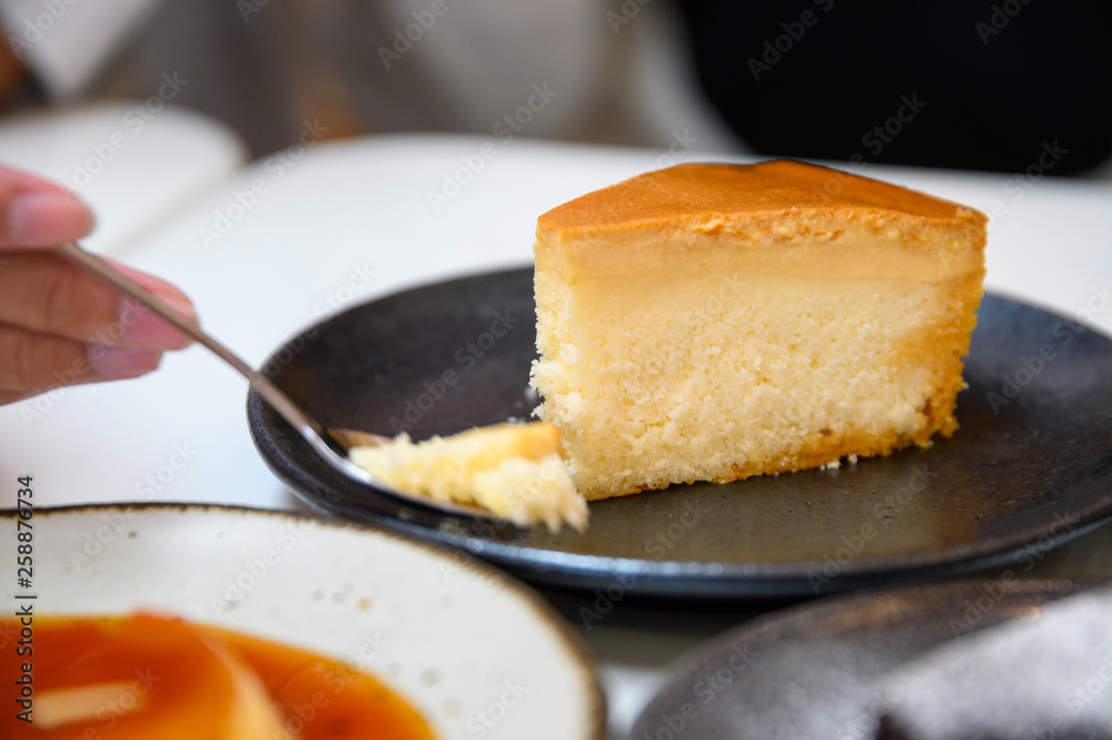 Spoon scooping custard cheesecake on dish