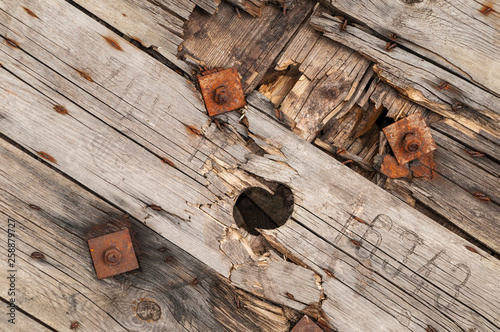 Background, damaged construction out of weathered wood plancs with rusty screws photo