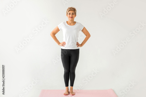 stylish elderly woman doing yoga on a white background © Alexandr