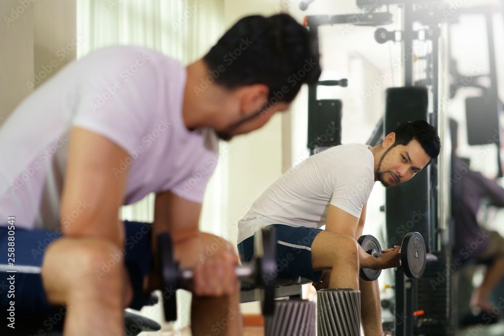 Strong man sitting and workout lifting dumbbell for exercise in gym. Strong man sitting and workout lifting dumbbell for exercise in gym.