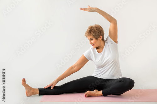stylish elderly woman doing yoga on a white background