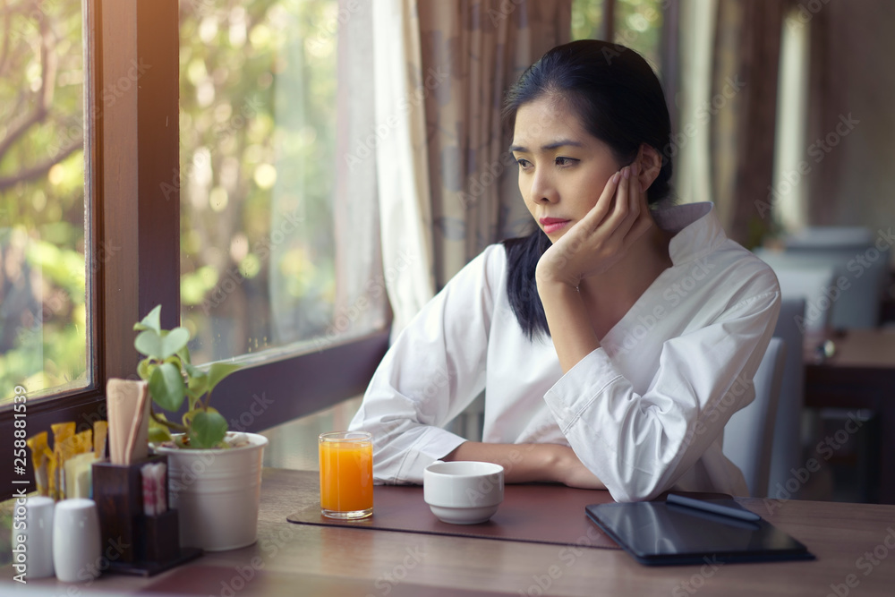 Lonely asian woman looking through a window sitting alone in the restaurant.. Lonely asian woman looking through a window sitting alone in the restaurant..