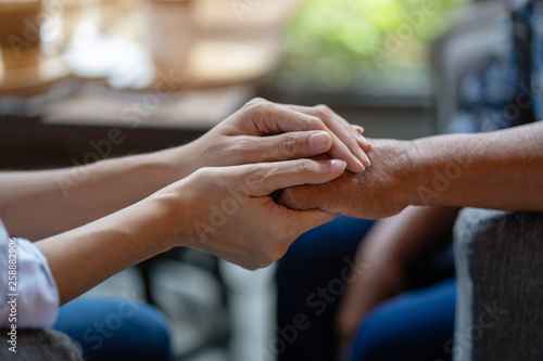 Fotografie, Obraz Hand of younger woman holding hand elderly woman, Helping hands, Take care for the elderly concept