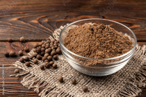 Black pepper on dark wooden background. 
