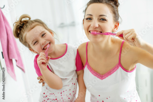 Woman and child brush their teeth 