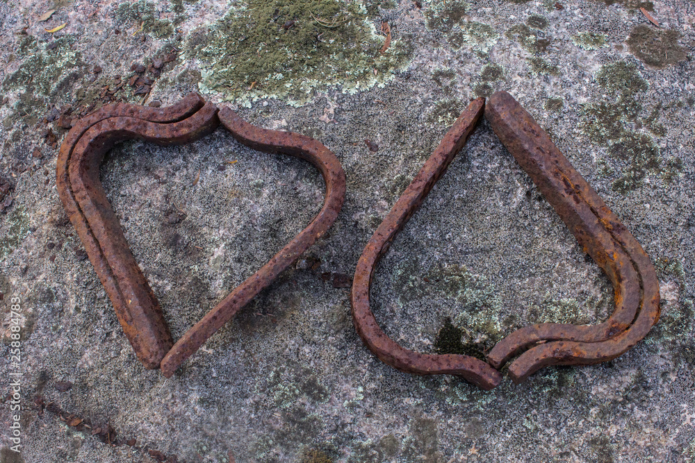 Old rusty railway spikes arranges to look like hearts on a rock with lichen Old rusty railway spikes arranges to look like hearts on a rock with lichen