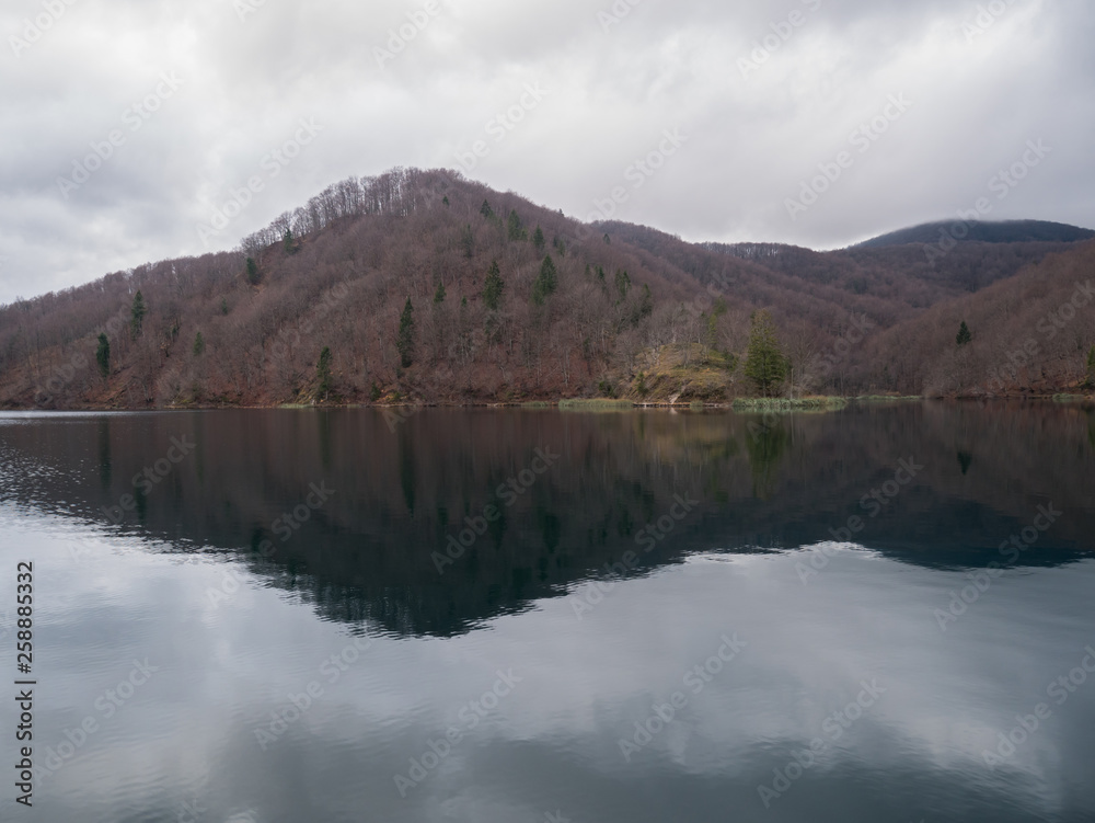 Calm lake water with reflection on cloudy winter day