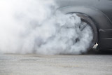 Racing Car Burning rubber Tire on Spinning wheel with white smoke