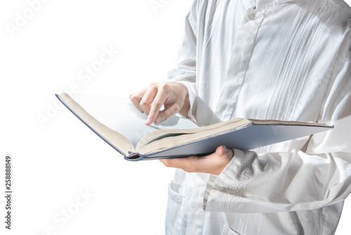 Muslim man standing while reading the quran on his hands