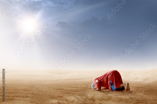 Photo Rear view of asian muslim man praying in prostration position on desert