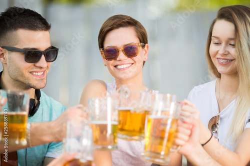 Young group of happy and beautiful people with a beer outdoors