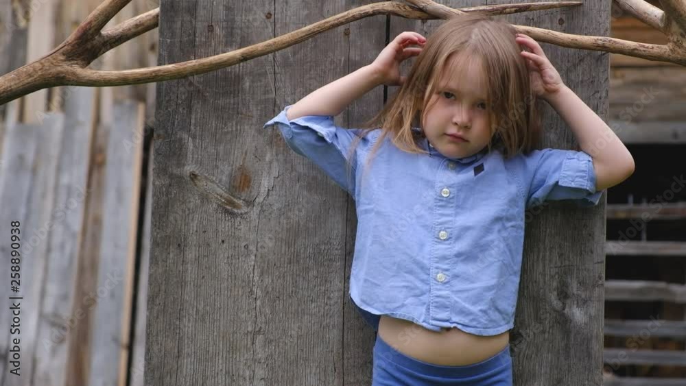 Little cute girl in stylish clothes posing against the background of a wooden screen Little cute girl in stylish clothes posing against the background of a wooden screen