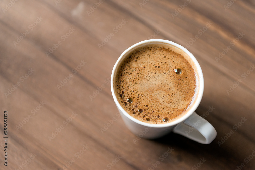 black coffee with foam in a mug on a wooden background black coffee with foam in a mug on a wooden background