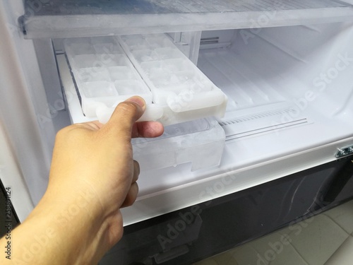 Man hand twisting for ice from the ice maker in new refrigerator.Closed up.