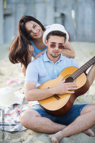Young couple with a guitar at the beach