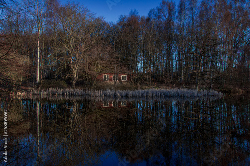 red house reflected in lake and landscape with trees
