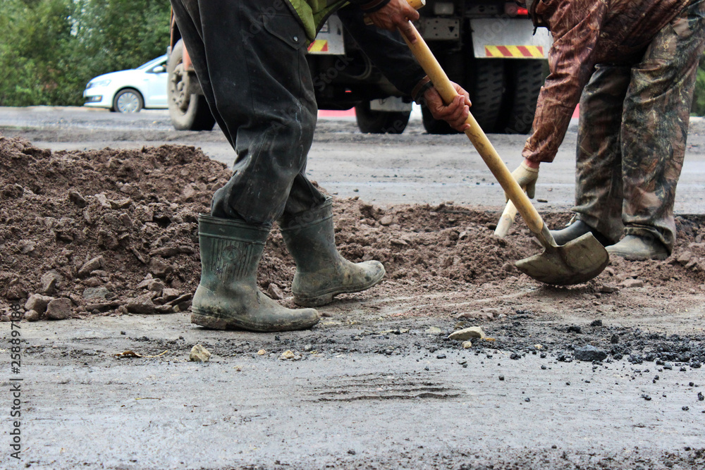 workers with shovels prepare part of the road for asphalting using the patch method. repair and expansion of the road. Gatchina, reportage. workers with shovels prepare part of the road for asphalting using the patch method. repair and expansion of the road. Gatchina, reportage.
