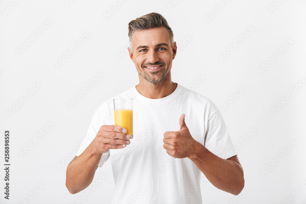 Image of european man 30s with bristle wearing casual t-shirt holding glass of orange juice Image of european man 30s with bristle wearing casual t-shirt holding glass of orange juice