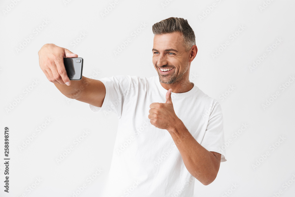 Successful man 30s wearing casual t-shirt looking on camera while taking selfie photo Successful man 30s wearing casual t-shirt looking on camera while taking selfie photo