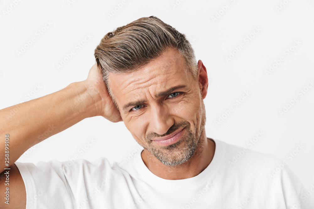 Image of exhausted man 30s with bristle wearing casual t-shirt grabbing head due to pain
