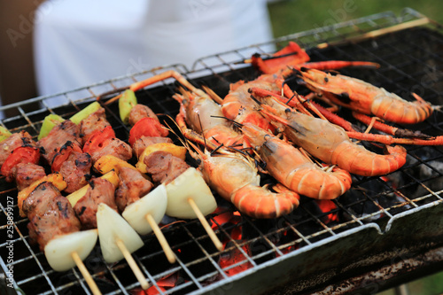 Roasted prawns and pork with vegetable kebabs on barbecue grilling stove.