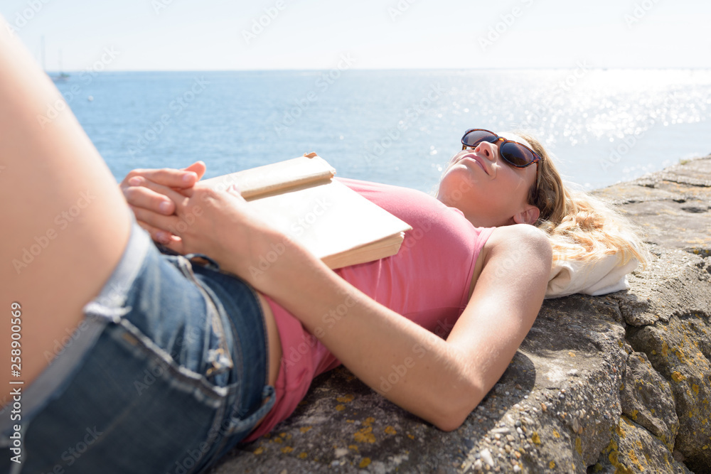 woman reading a book on the beach at sunset