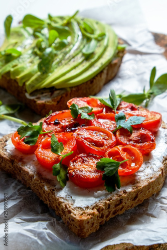Healthy vegan breakfast concept. Vegetarian cheese spread sandwich, ripe avocado slices, sun dried tomato, toasted bread. clean eating. White table background. Top view, close up, copy space, flat lay