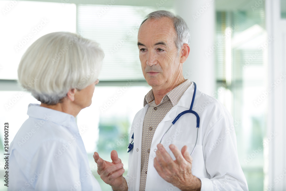 doctor talking to senior female patient in the corridor doctor talking to senior female patient in the corridor