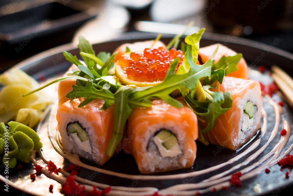A plate of sushi with salmon, caviar, arugula/rucola/ruccola/rocca salad and wasabi, close up, back view, horisontally. A plate of sushi with salmon, caviar, arugula/rucola/ruccola/rocca salad and wasabi, close up, back view, horisontally.