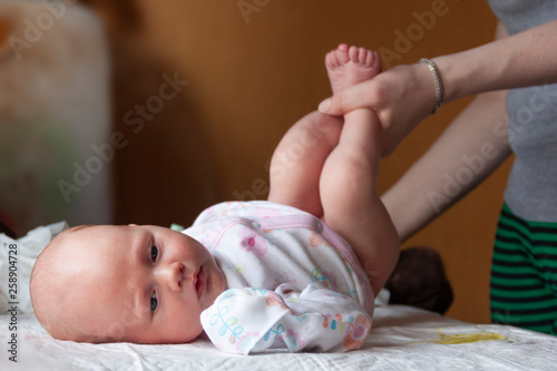 The newborn lies on his back while his mother changes his diaper