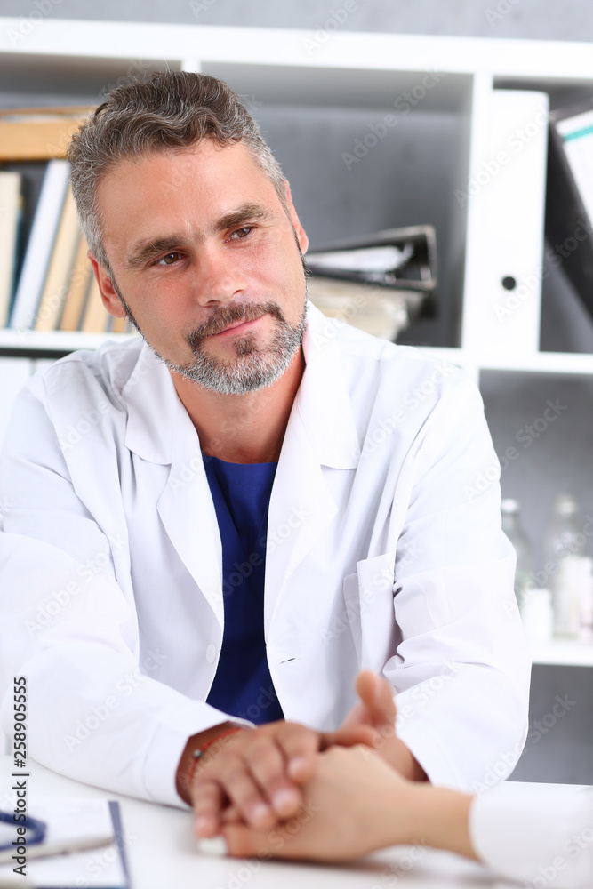 Friendly male doctor hold female arm in office Friendly male doctor hold female arm in office