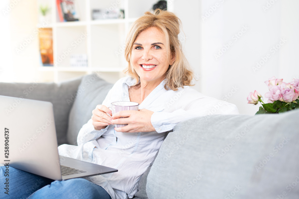 Frau in mittlerem Alter genießt eine Tasse Kaffe zuhause auf der Couch Frau in mittlerem Alter genießt eine Tasse Kaffe zuhause auf der Couch