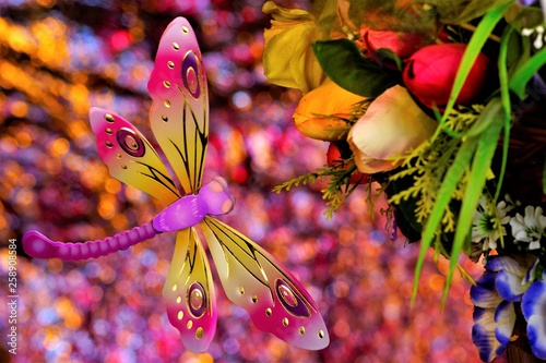 Summer concept, dragonfly flies on a bouquet of flowers, on a rainbow bokeh background. Flowers garden decoration pleasing to the eye, in harmony with life, represent the beauty of a symbol of love an