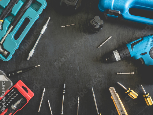 top view of Construction tools concept with Drill sets, hammer, screwdriver and Toolbox on black wooden background.