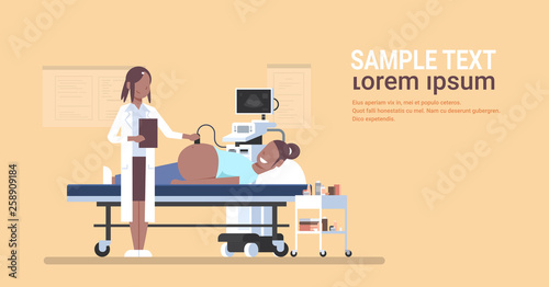 pregnant woman visiting afican american doctor doing ultrasound fetus screening at digital monitor gynecology consultation concept hospital clinic horizontal full length copy space